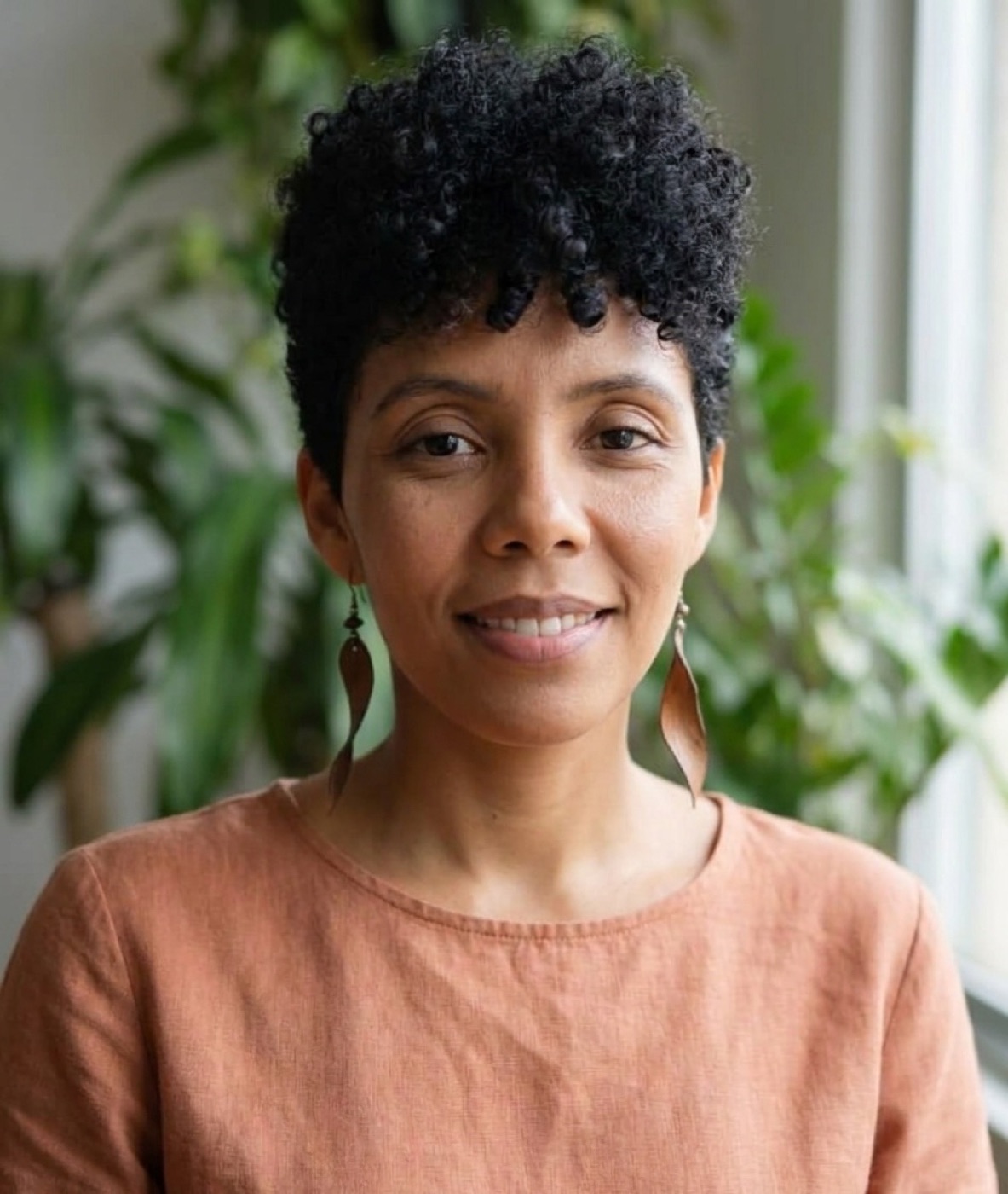 Retrato de Luciane Oliveira, terapeuta naturista, sorrindo em meio a plantas